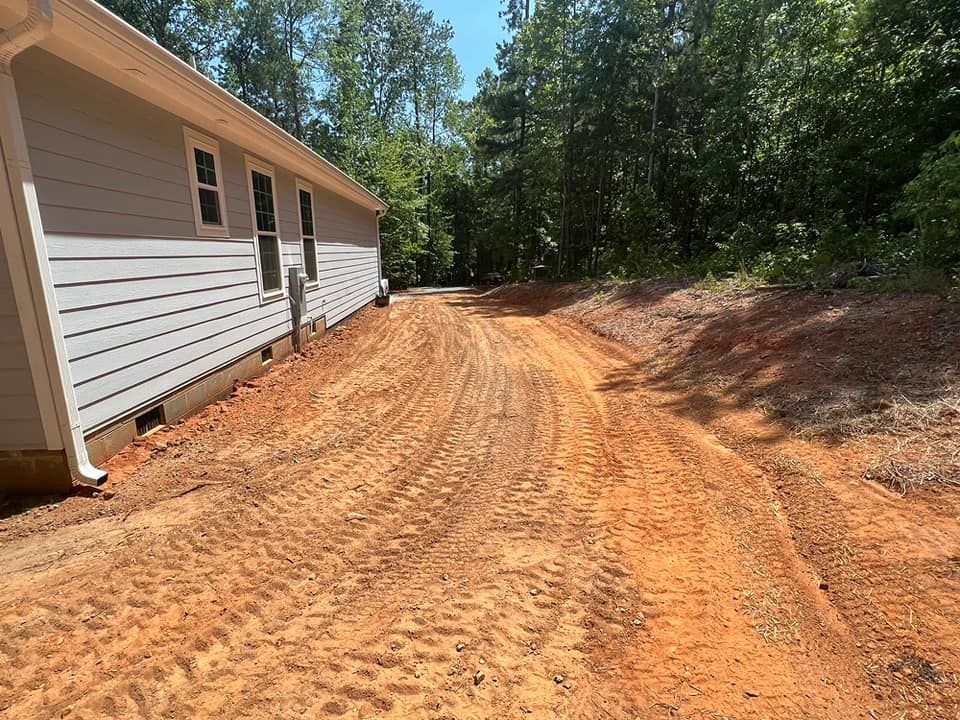 A dirt road leading to a house in the woods.