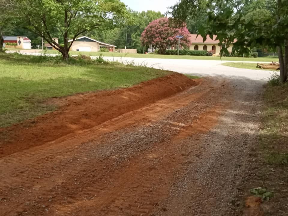A dirt road with a house in the background