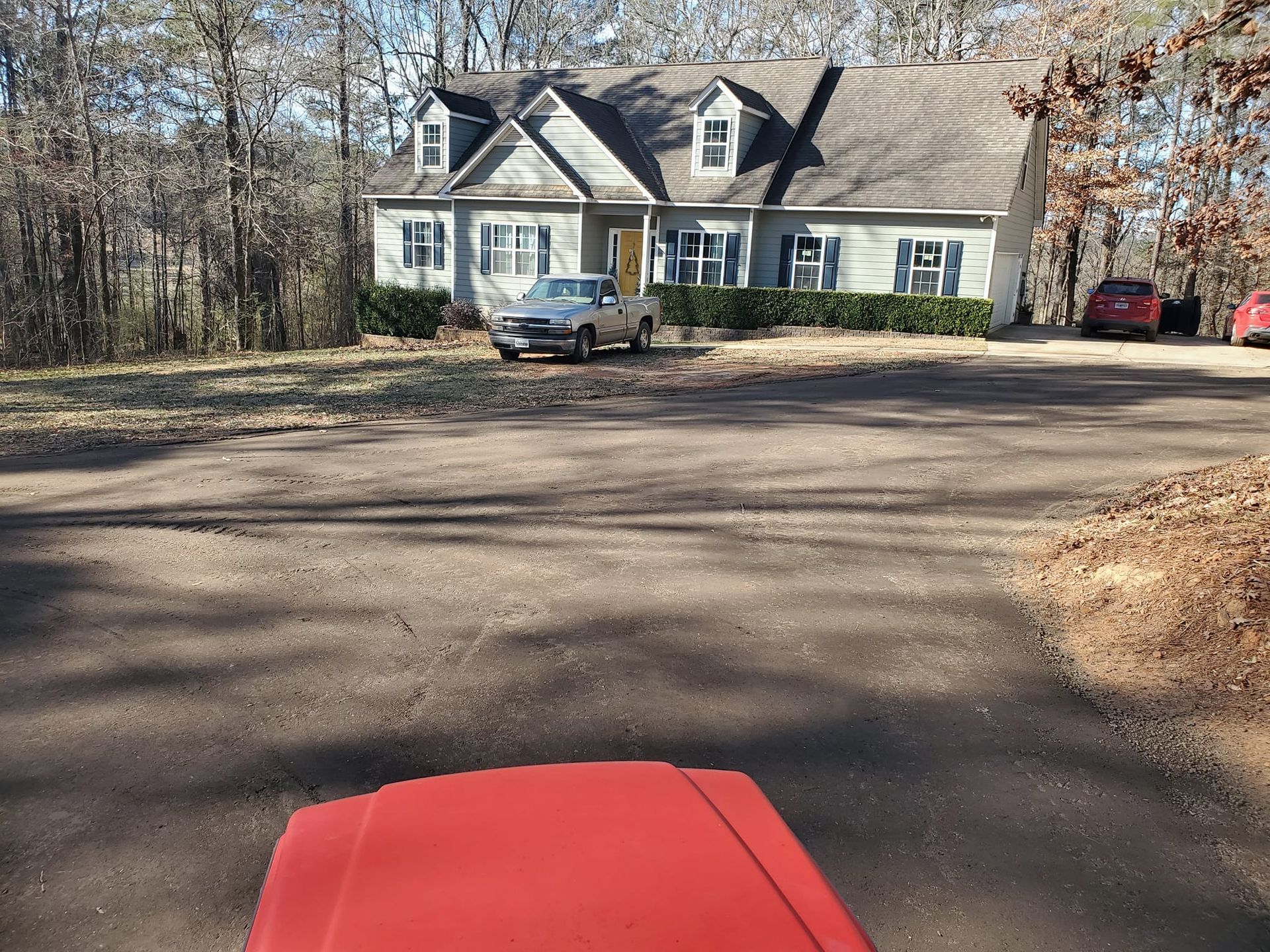 A red truck is parked in front of a large house.