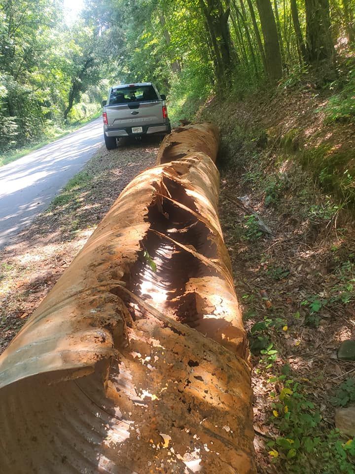 A truck is parked on the side of a road next to a large log.