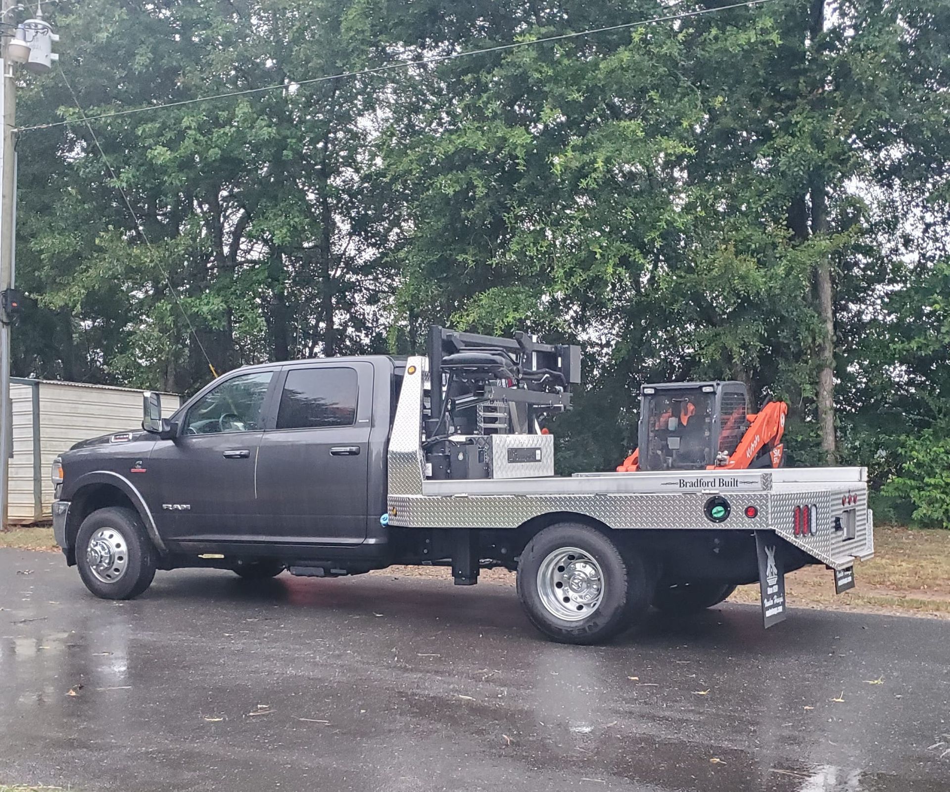 A black truck with a flatbed is parked on the side of the road