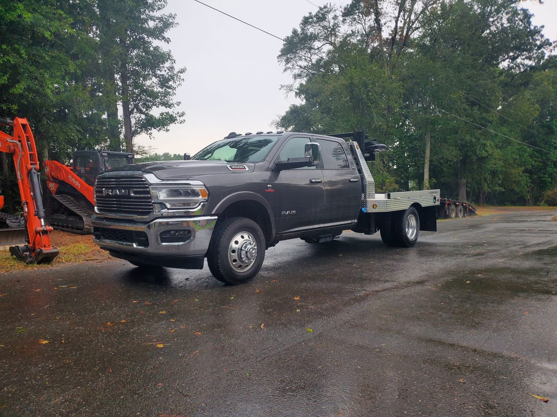 A ram truck with a flatbed trailer is parked on the side of the road.