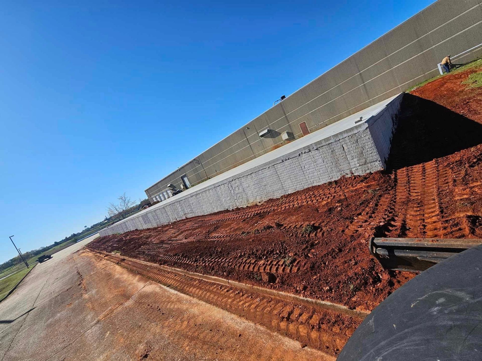 A large concrete wall is being built next to a dirt road.