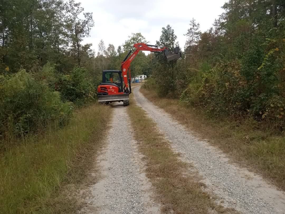 A red excavator is driving down a dirt road.
