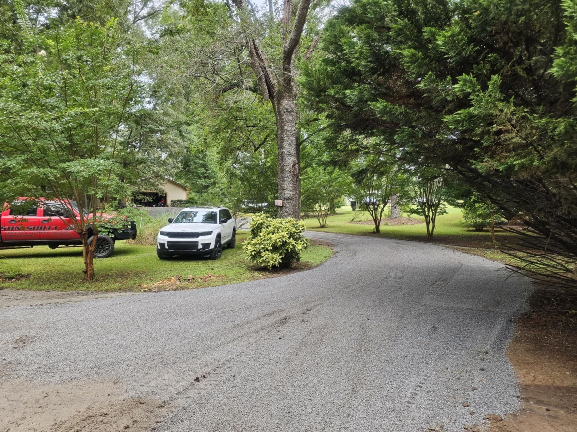 A white car is parked on the side of a gravel road.