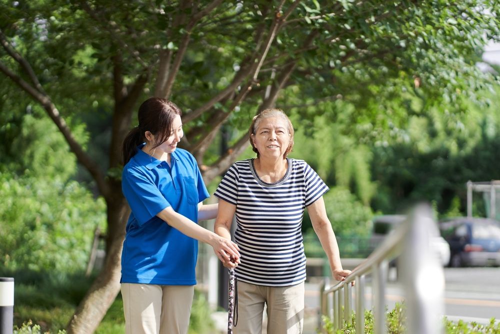 Elderly lady walking with the help of a female caregiver - First Aid in Mackay, QLD