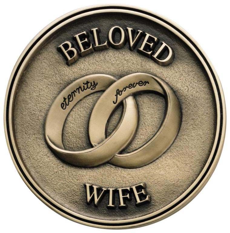 A coin that says beloved wife with two wedding rings on it