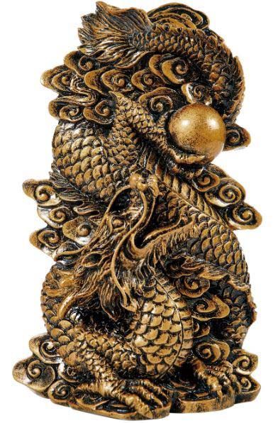 A statue of a dragon with a ball in its mouth.