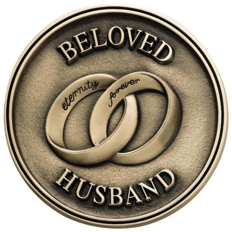 A coin that says beloved husband with two wedding rings on it