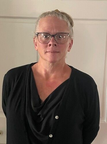 A woman with a tattoo on her arm is standing in a circle with her arms crossed.