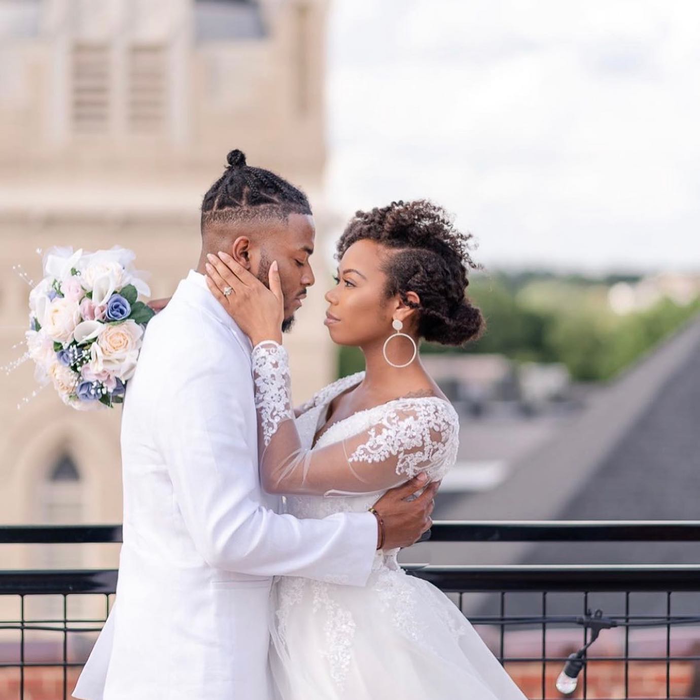 A bride and groom are kissing on a balcony.