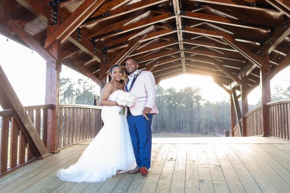A bride and groom are posing for a picture on a wooden bridge.