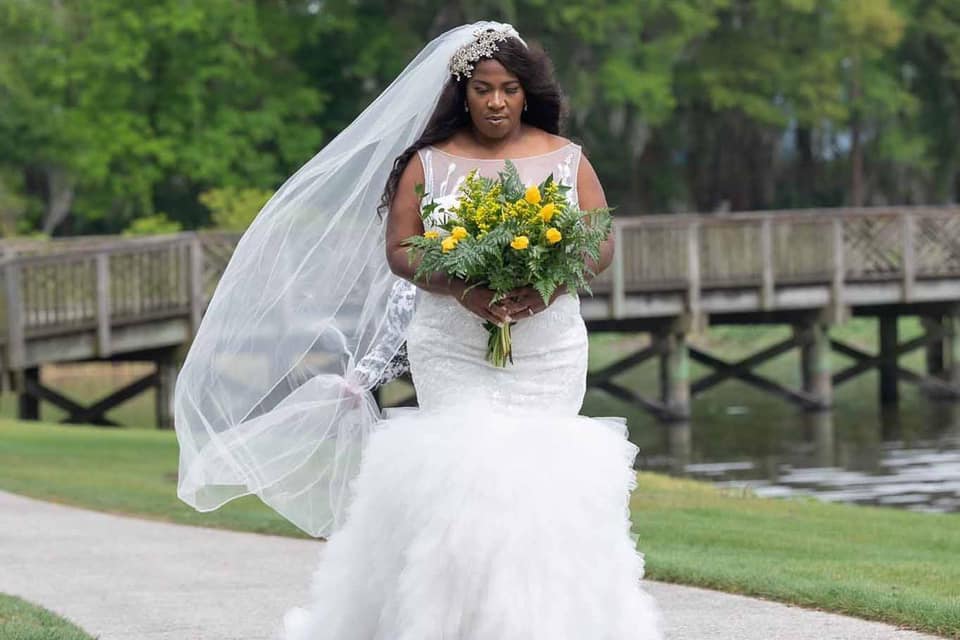 A bride in a wedding dress and veil is holding a bouquet of flowers.
