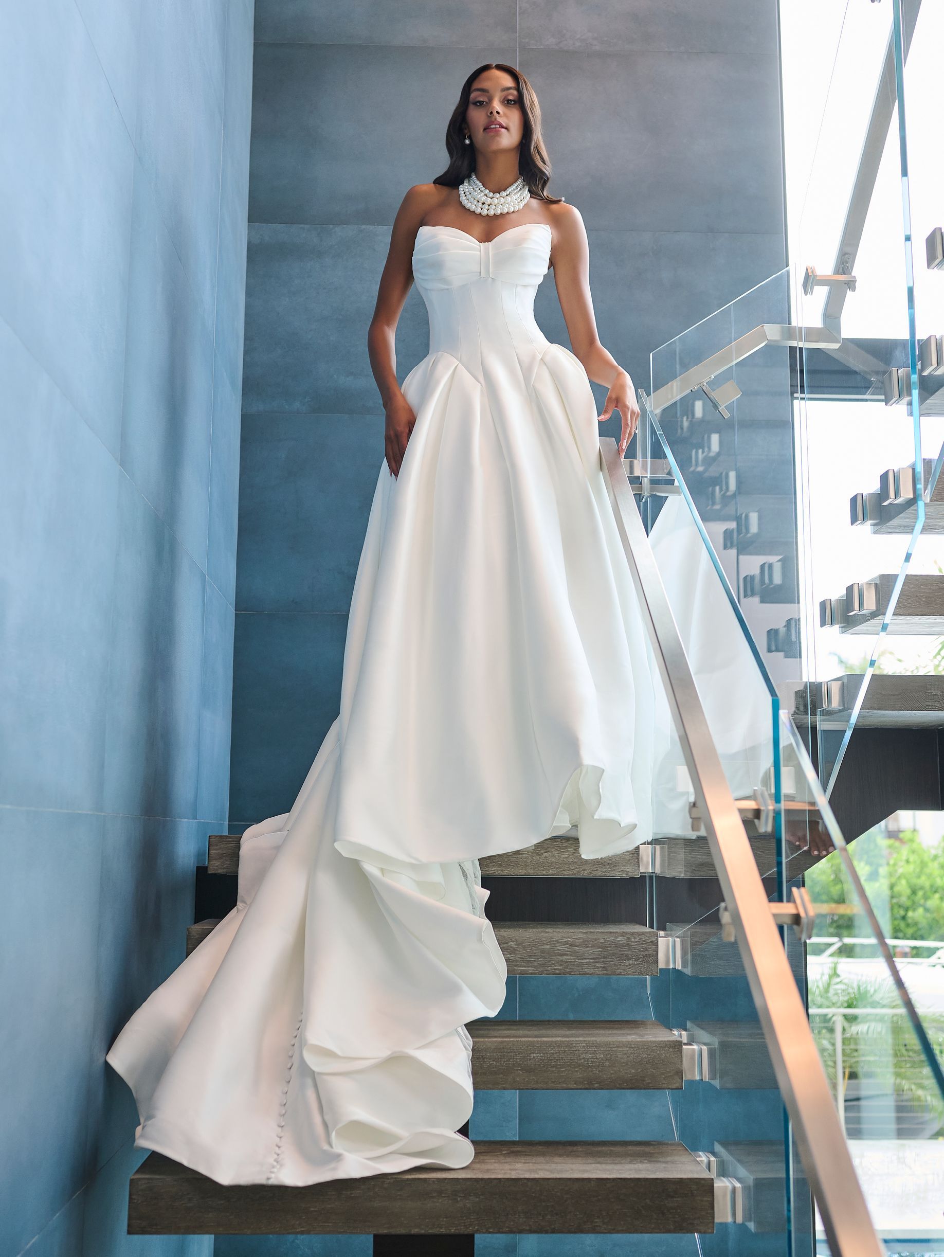 A woman in a white wedding dress is standing on a set of stairs.