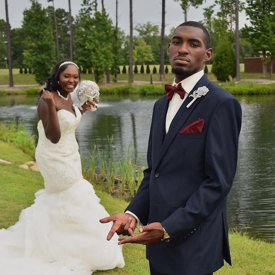 A bride and groom pose for a picture in front of a lake