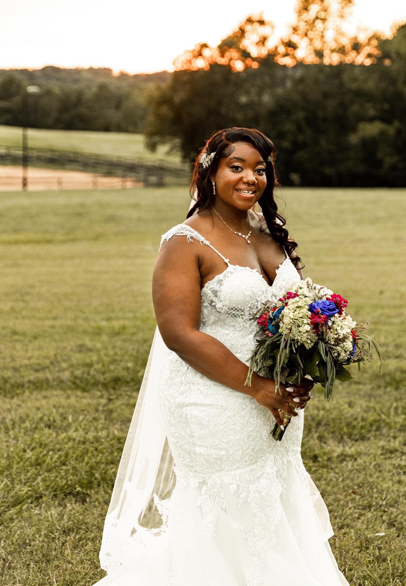 A woman in a wedding dress is holding a bouquet of flowers in a field.