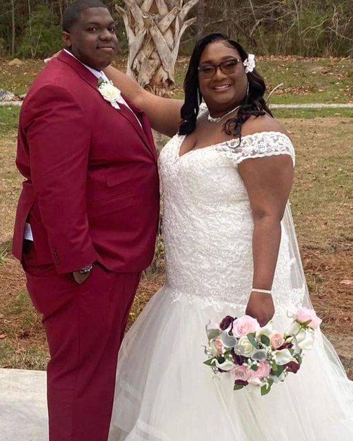 A bride and groom are posing for a picture in front of a palm tree.
