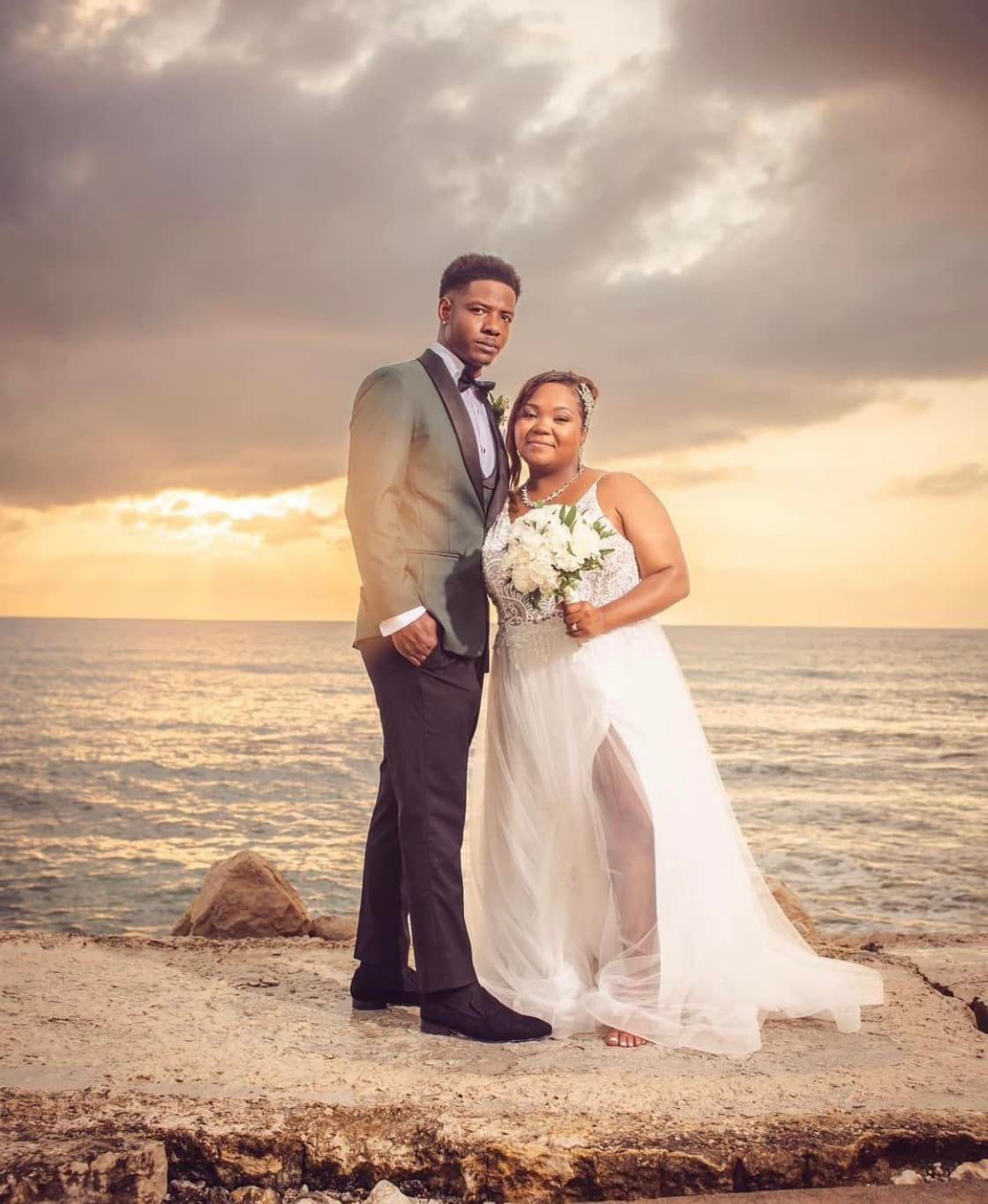 A bride and groom are posing for a picture on the beach.