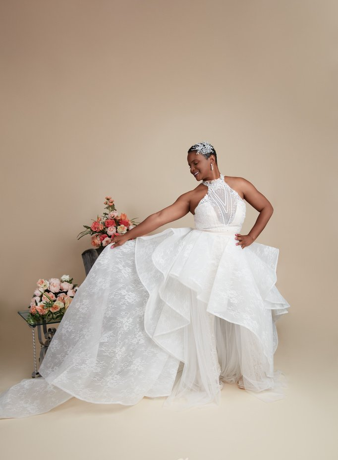 A woman in a white wedding dress is standing next to a vase of flowers.