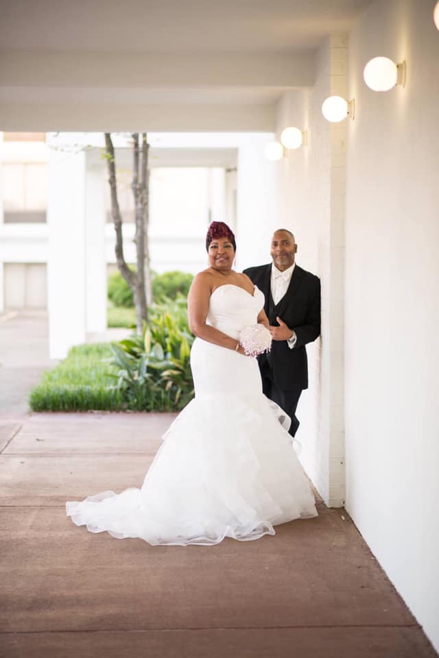 A bride and groom are posing for a picture in a hallway.