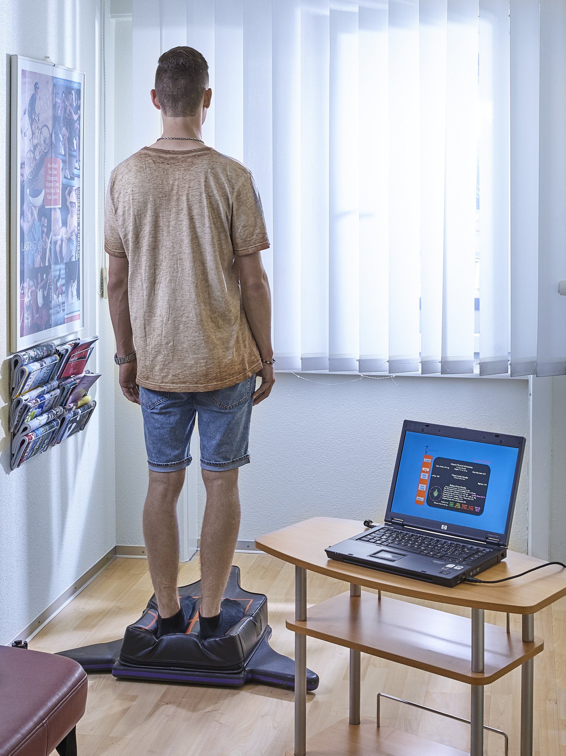 Ein Mann steht an einer Maschine vor einem Laptop.