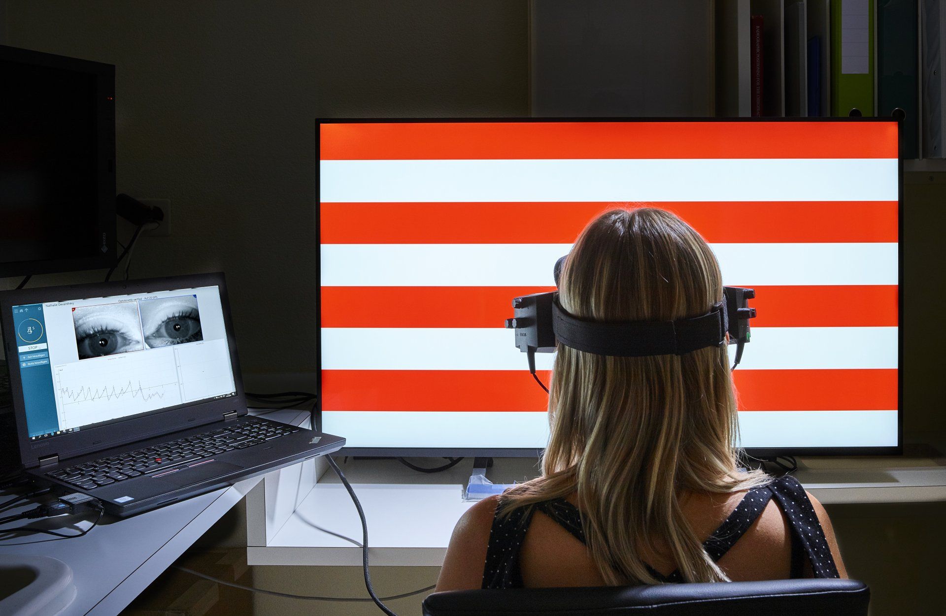 Eine Frau mit Kopfhörern sitzt vor einem Computermonitor.