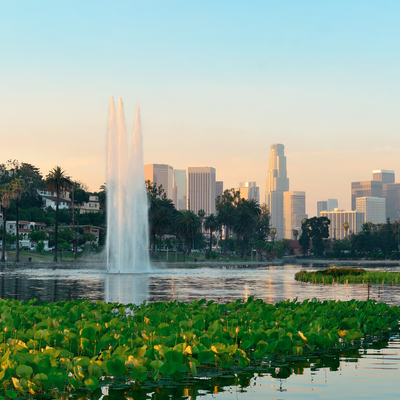 A fountain is spraying water over a lake with a city skyline in the background.