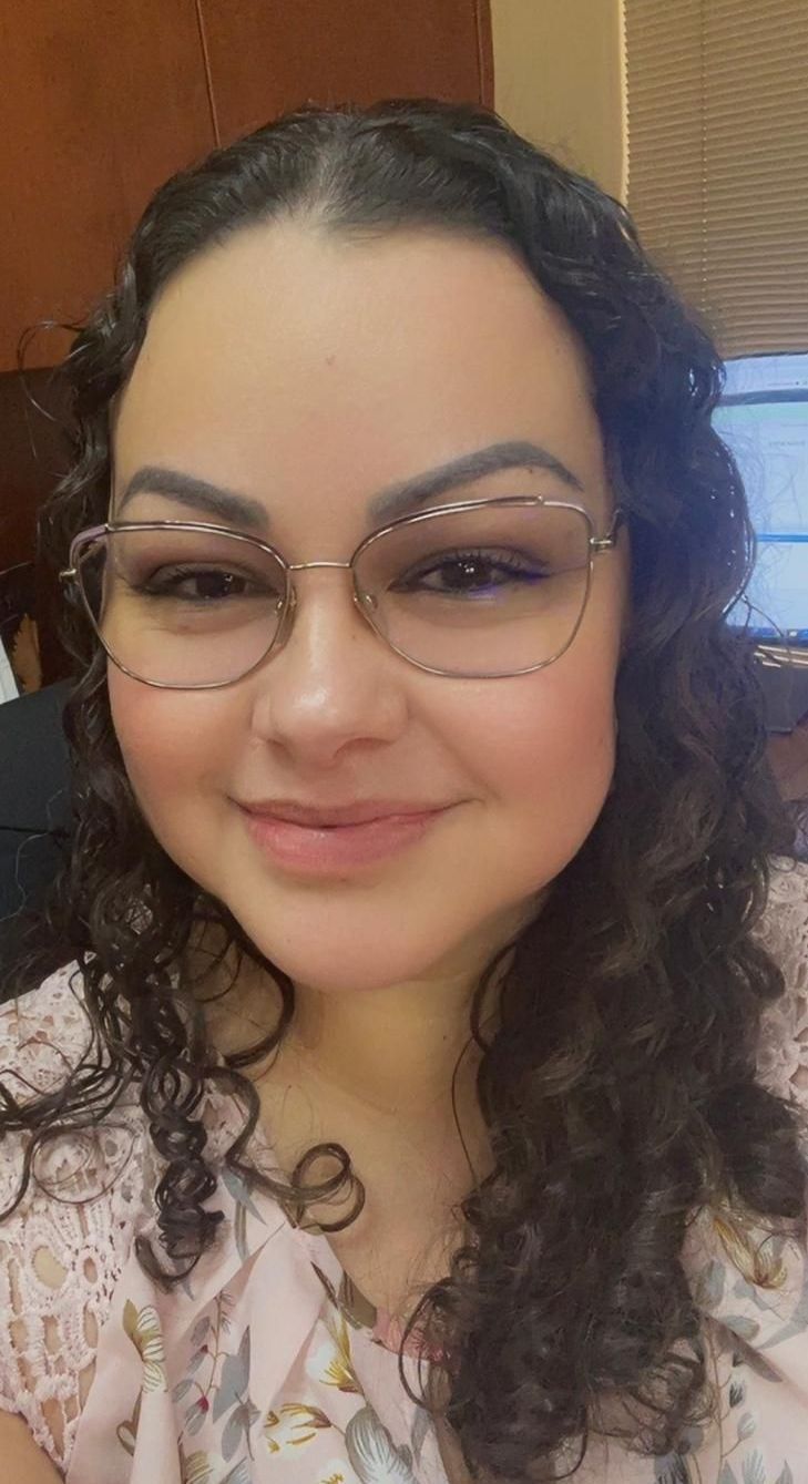 Agent Elsa is wearing glasses and smiling for the camera