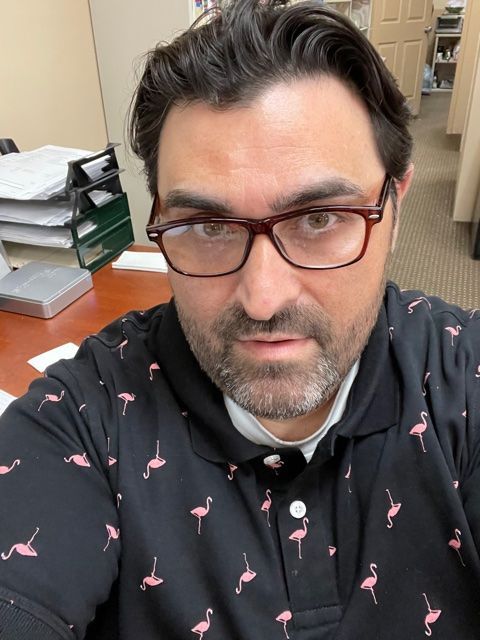 Agent Sal is wearing glasses and a flamingo shirt is taking a selfie.