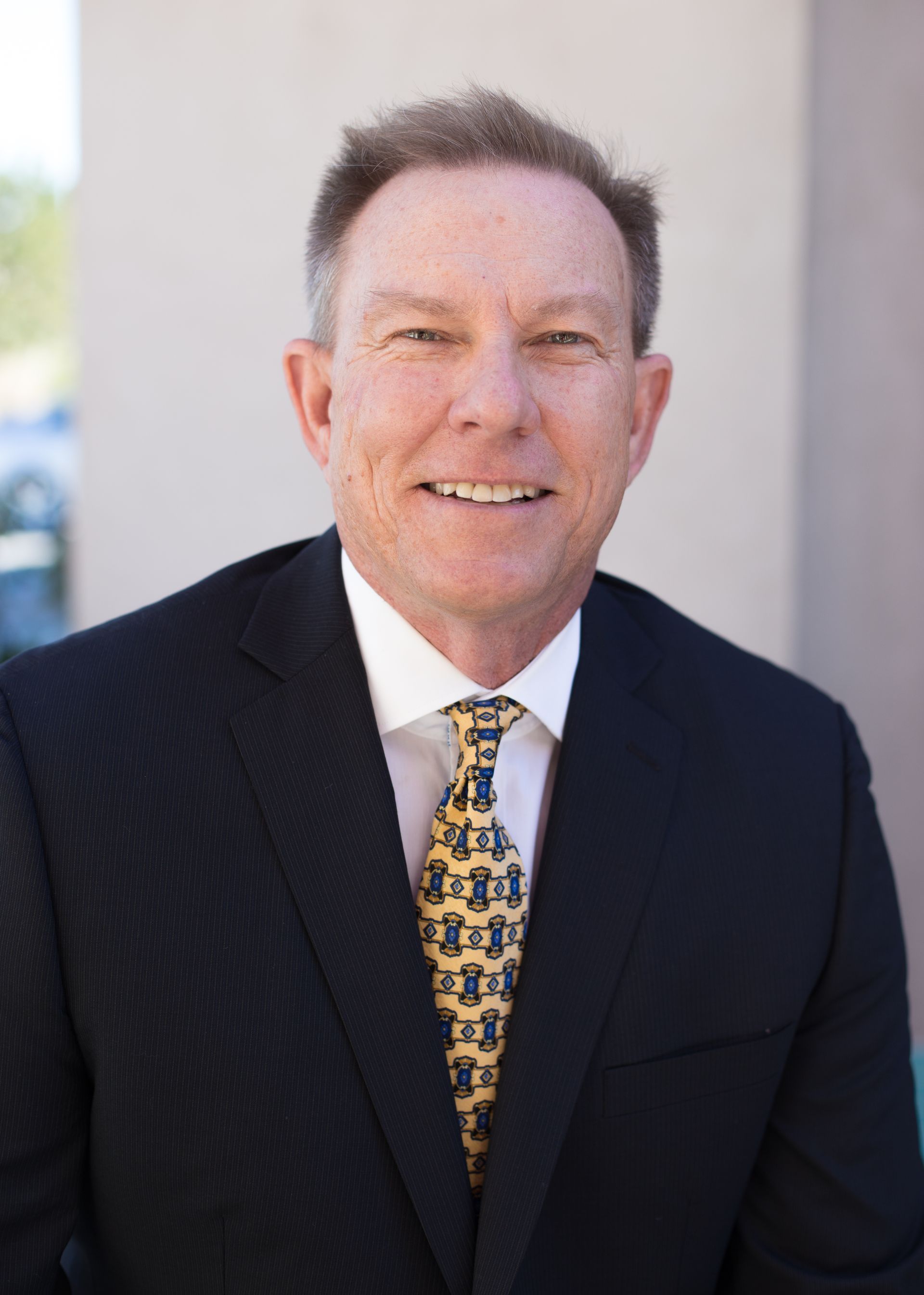 Agency founder Tom Breitfeller in a suit and tie is smiling for the camera.