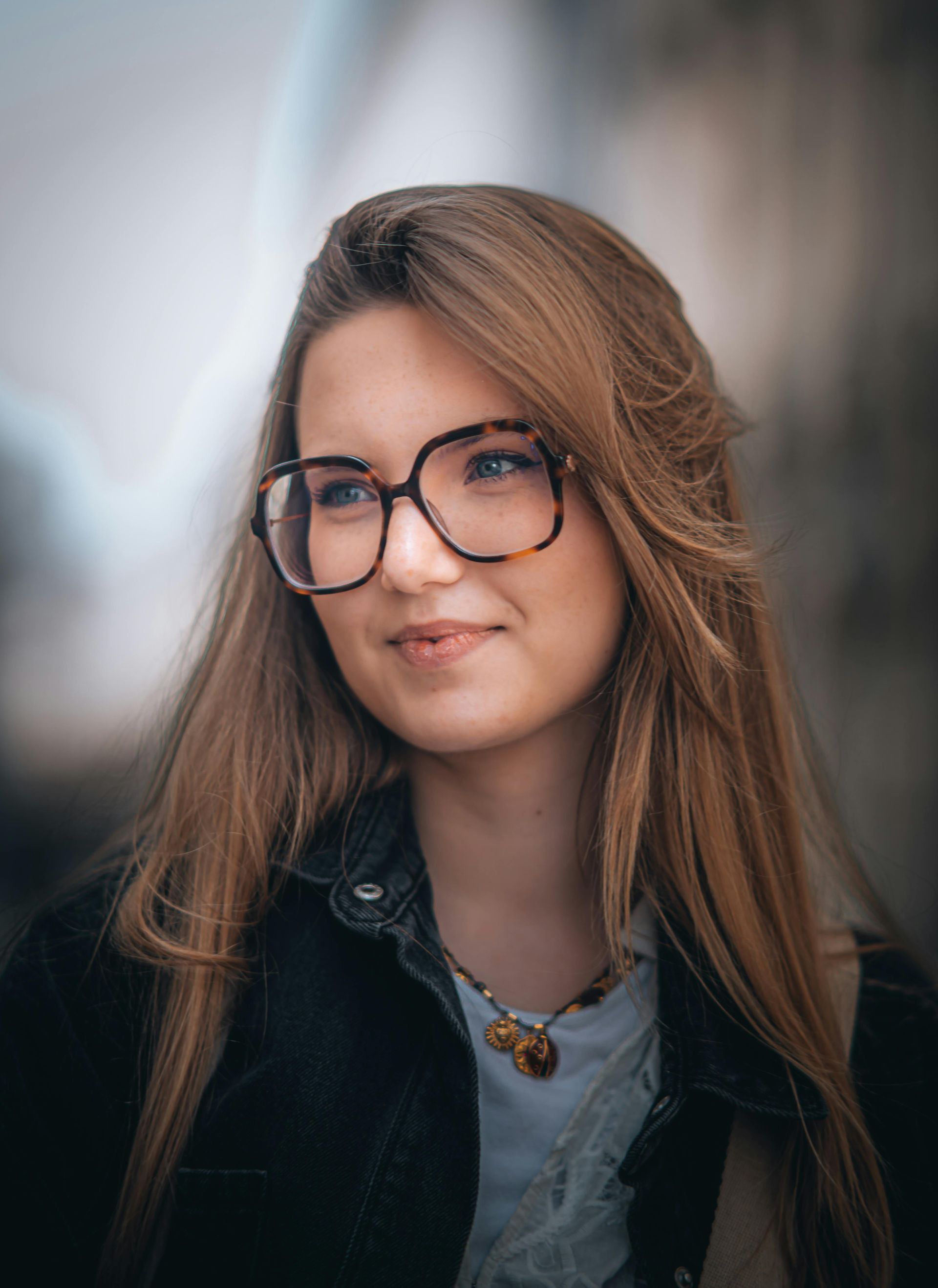 A close up of a woman wearing glasses and a necklace.