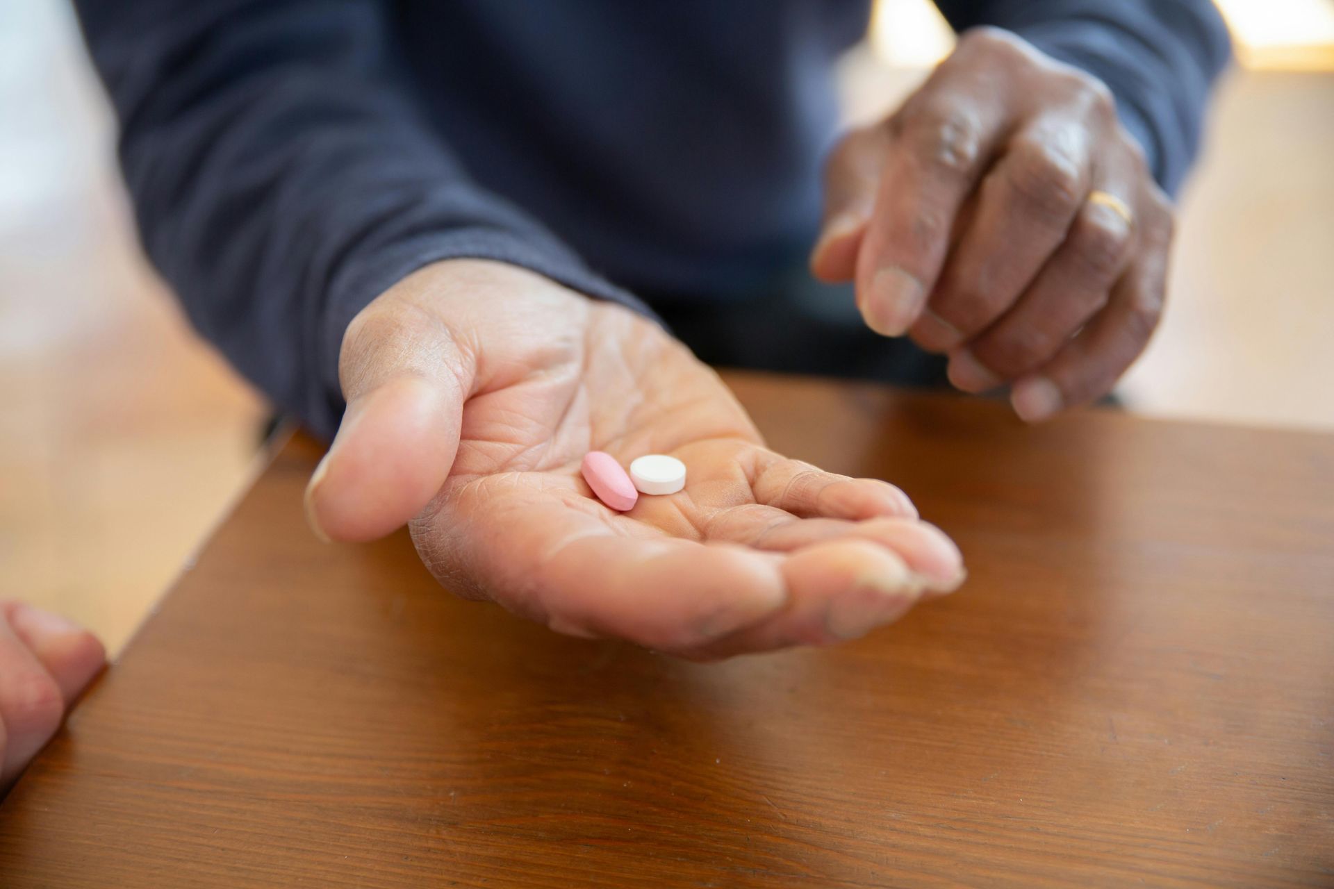A person is holding two pills in their hand.