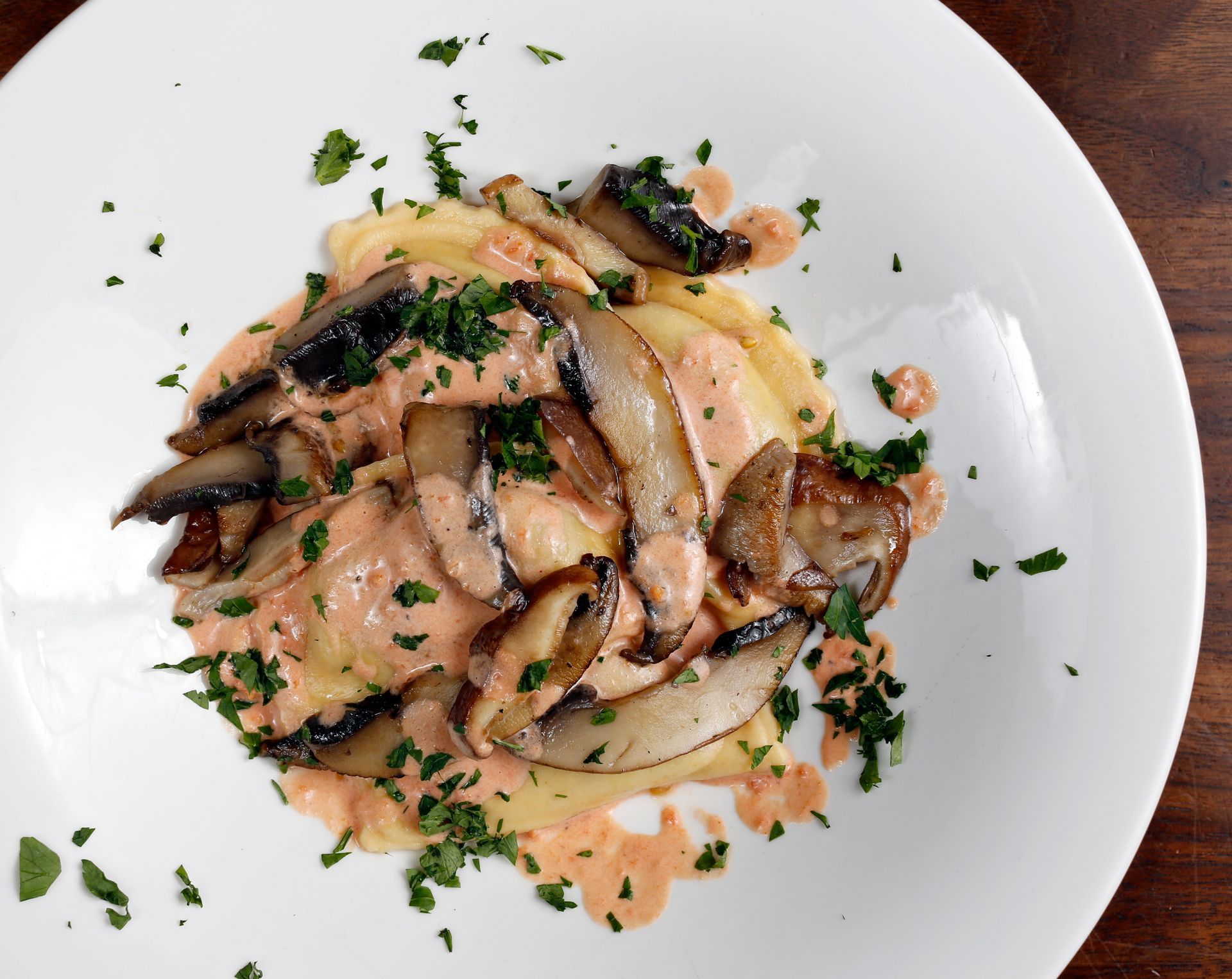 A white plate topped with pasta and mushrooms on a wooden table