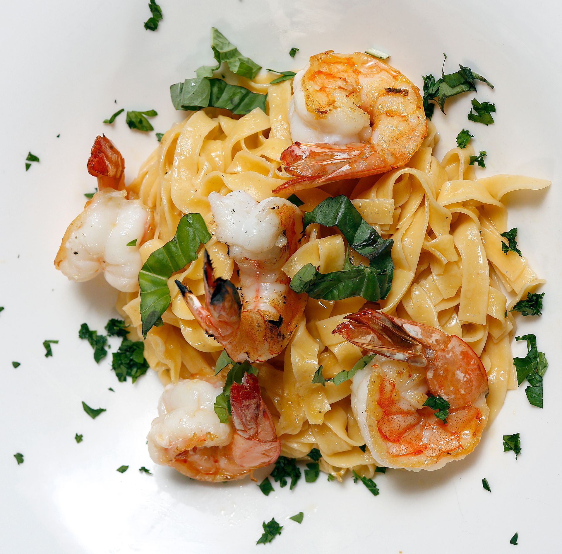 A plate of pasta with shrimp and parsley on it