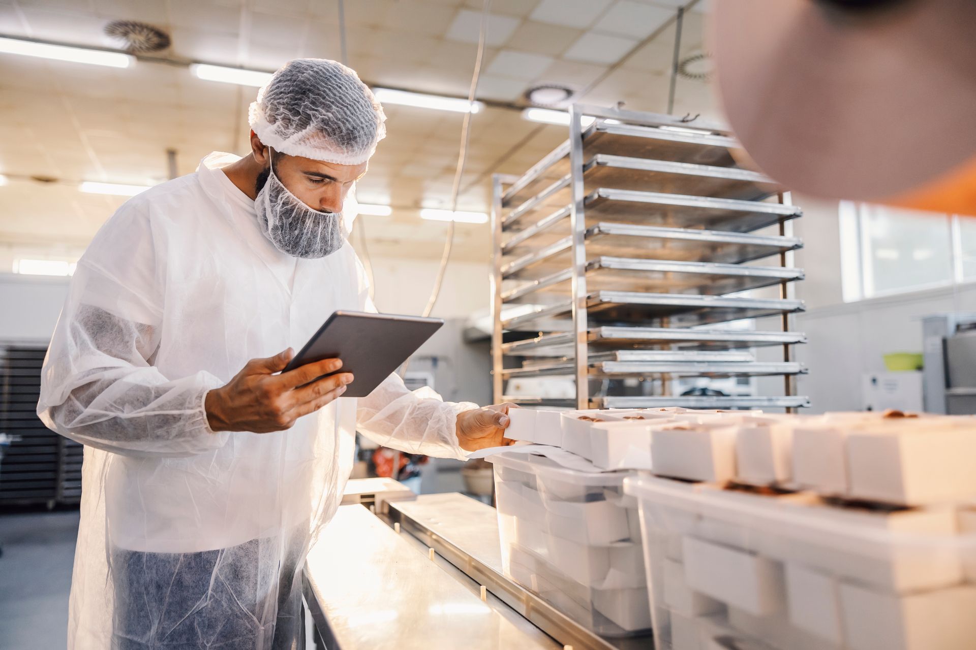 A man is looking at a tablet in a factory.