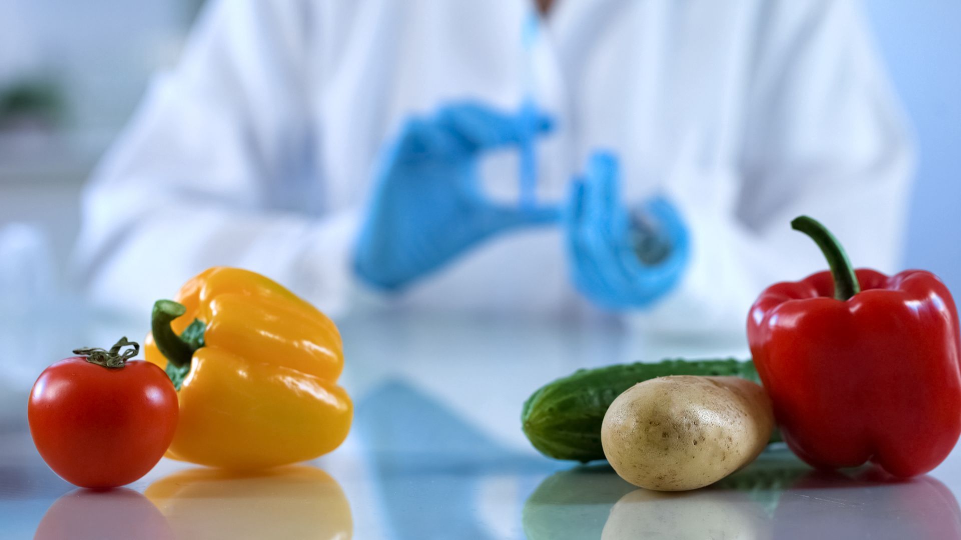 A scientist is holding a syringe in front of vegetables.