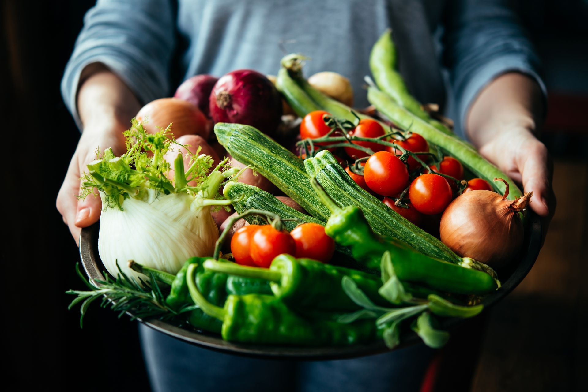 A person is holding a bowl of vegetables in their hands.