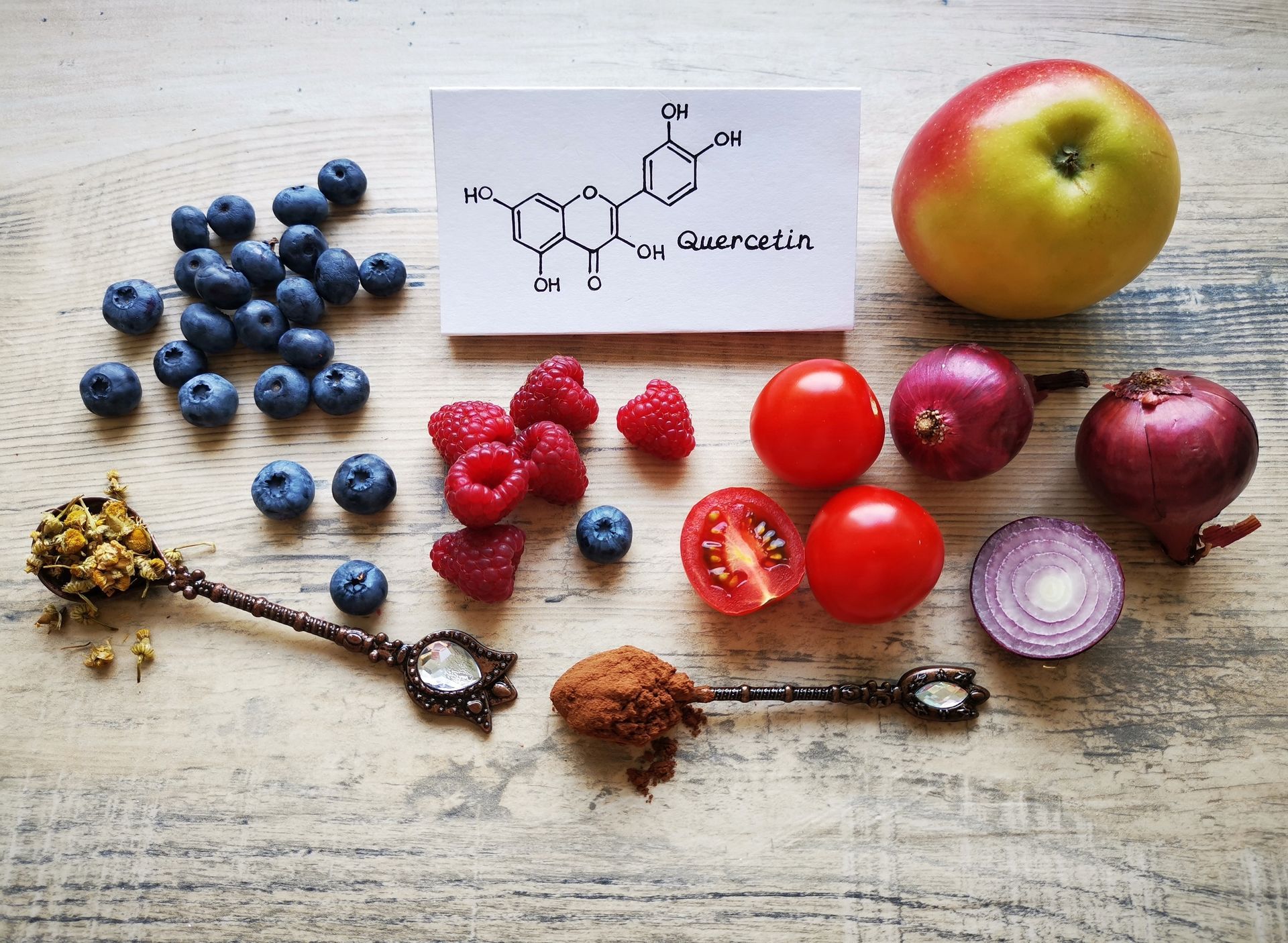 A wooden table topped with fruits , vegetables , spices and a chemical structure.