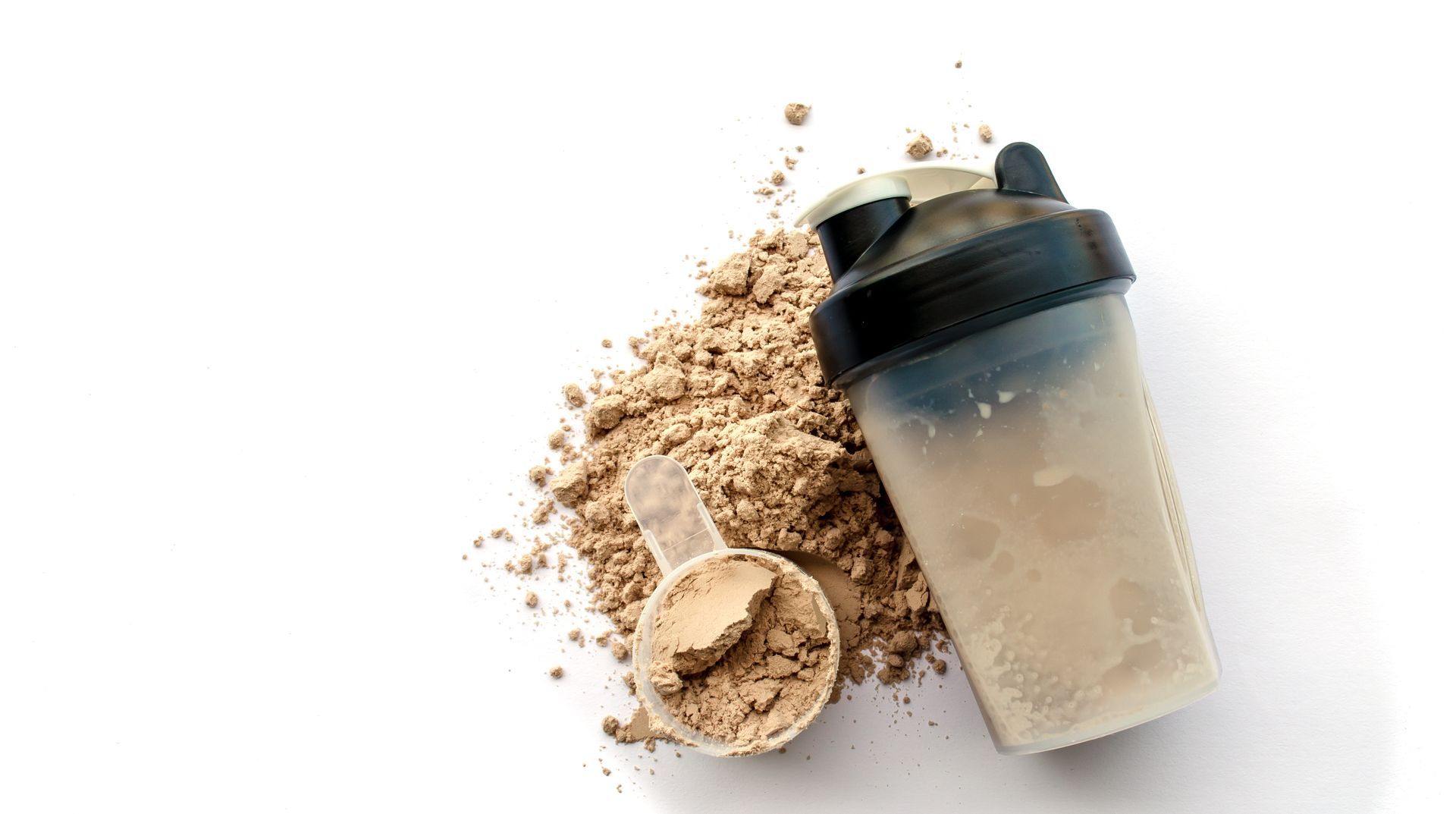 A shaker and a scoop of protein powder on a white background.