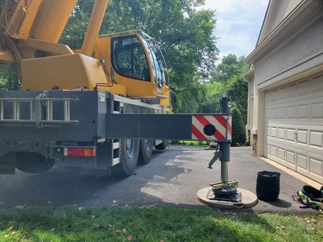 Yellow crane boom near a house. Stabilizer extended.