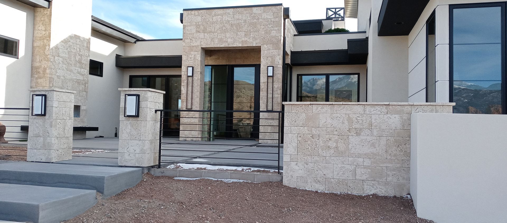 A house with a lot of tinted windows and a stone wall