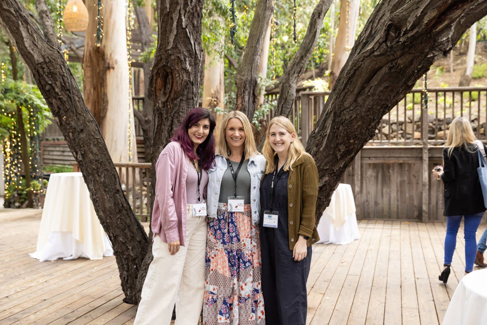 Three women are posing for a picture under a tree.
