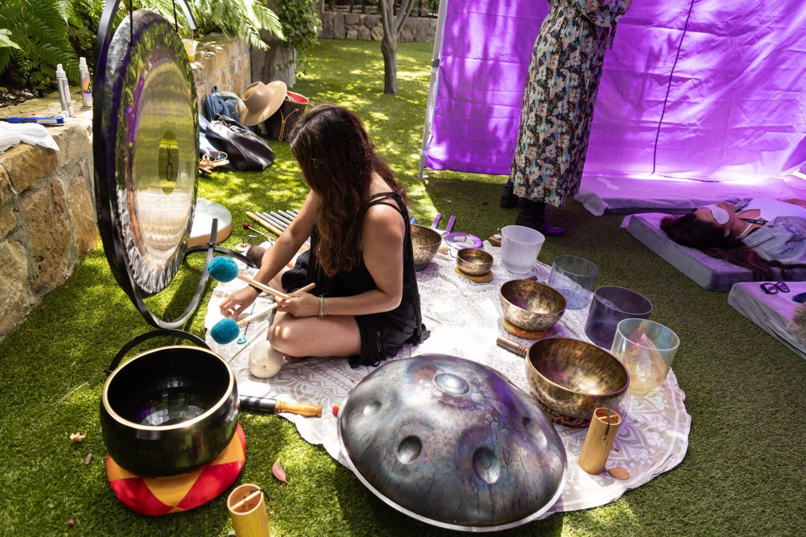 A woman is sitting on the grass playing a musical instrument.