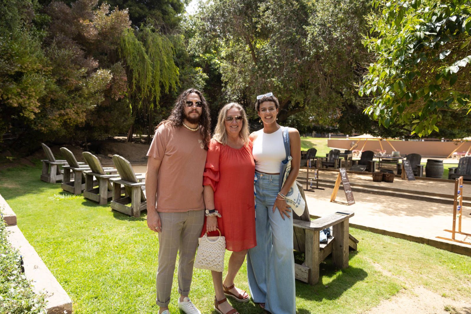 A man and two women are posing for a picture in a park.
