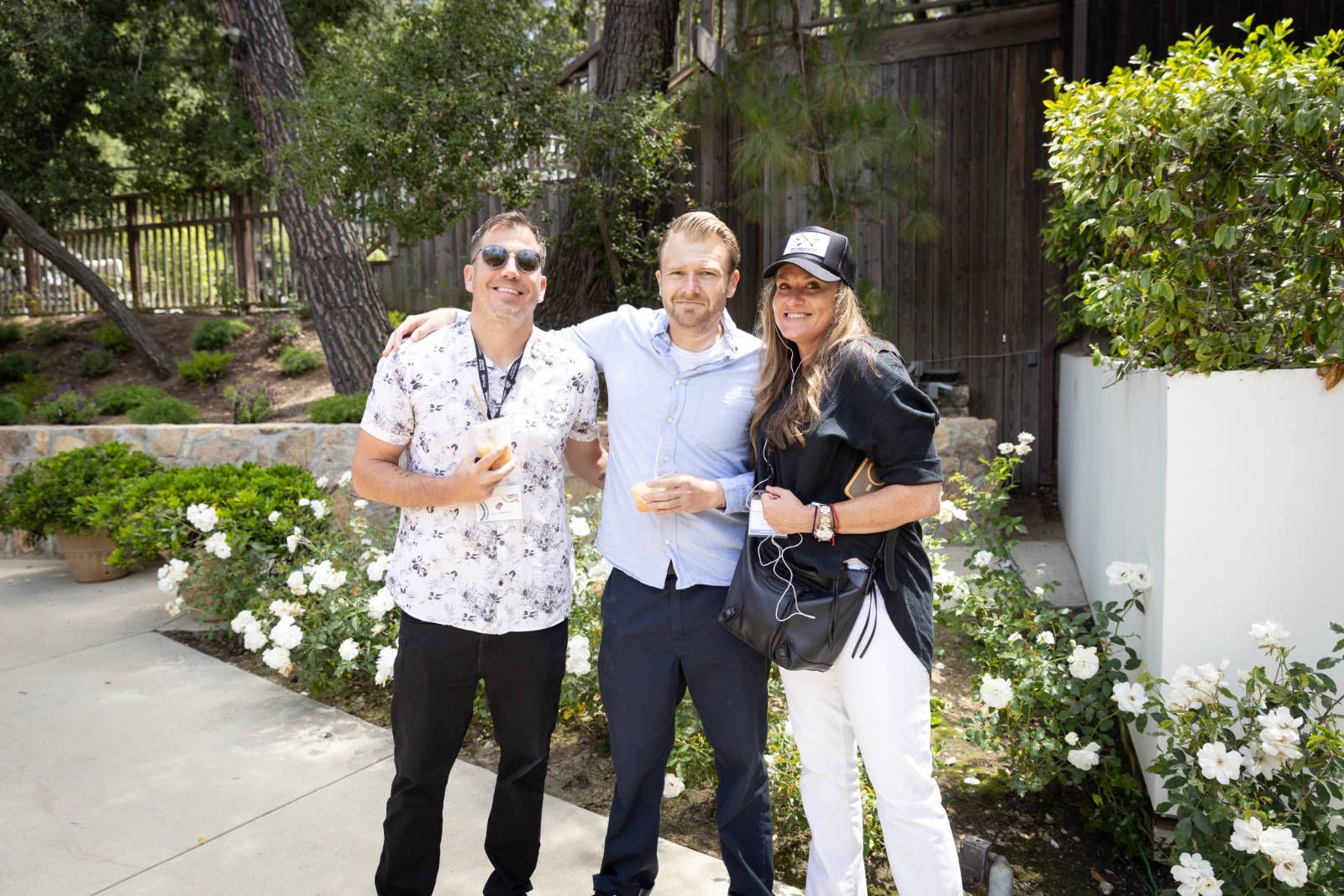 Three people are posing for a picture in front of a house.