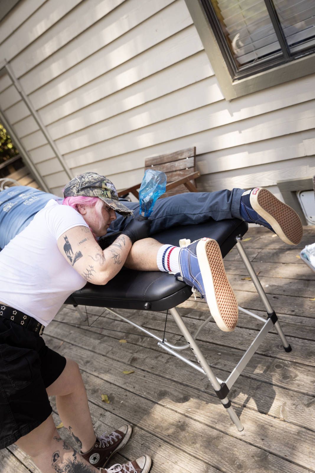 A man is laying on a table getting a tattoo on his leg.