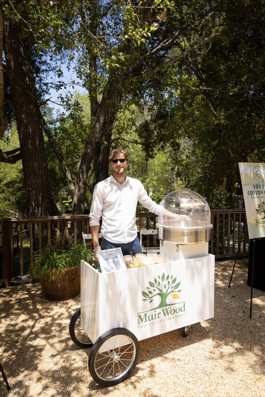 A man is standing next to a cart filled with cotton candy.