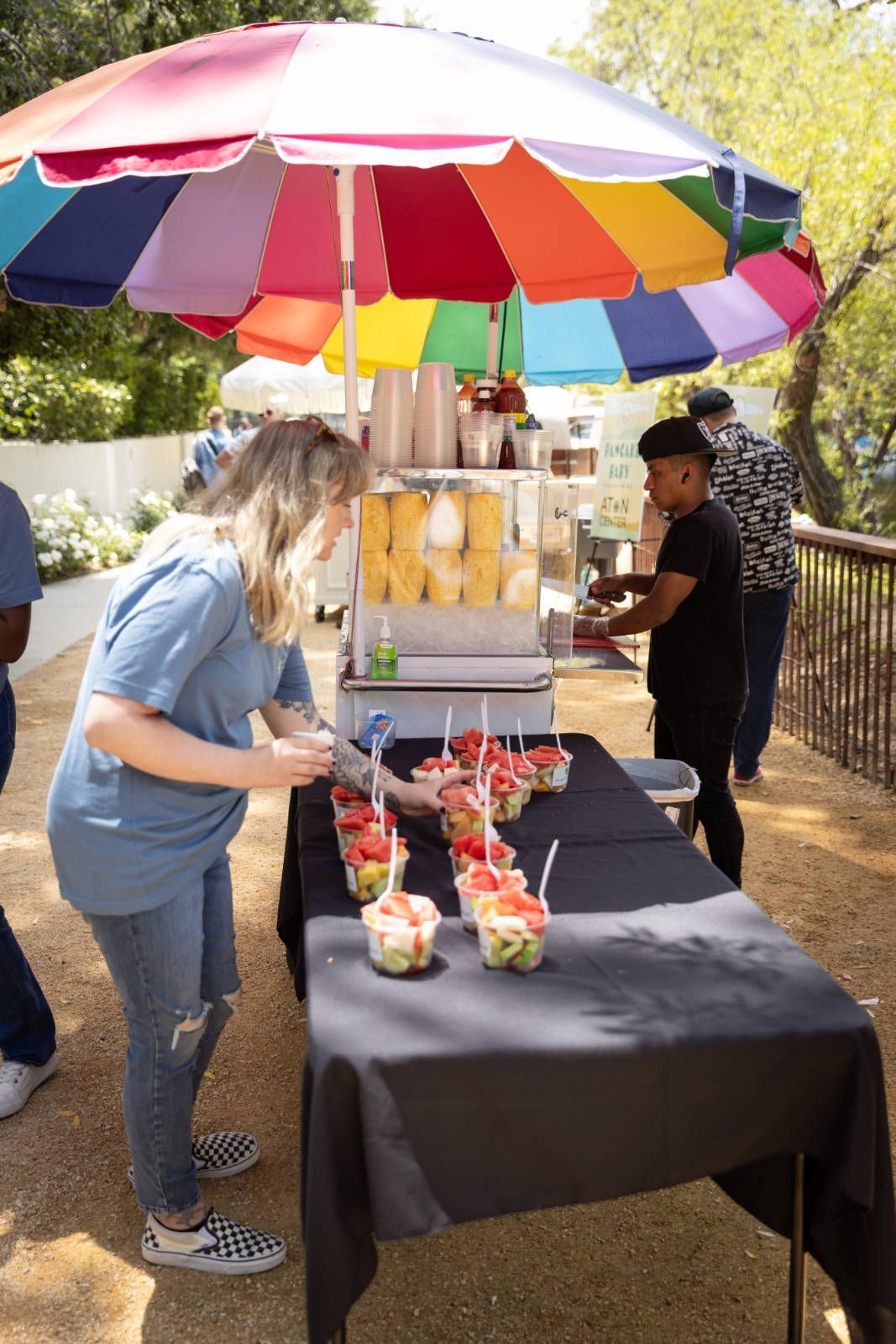 A woman is standing at a table with a colorful umbrella.