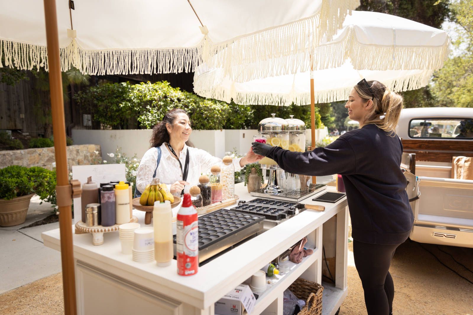 A woman is standing at a table serving food to another woman.