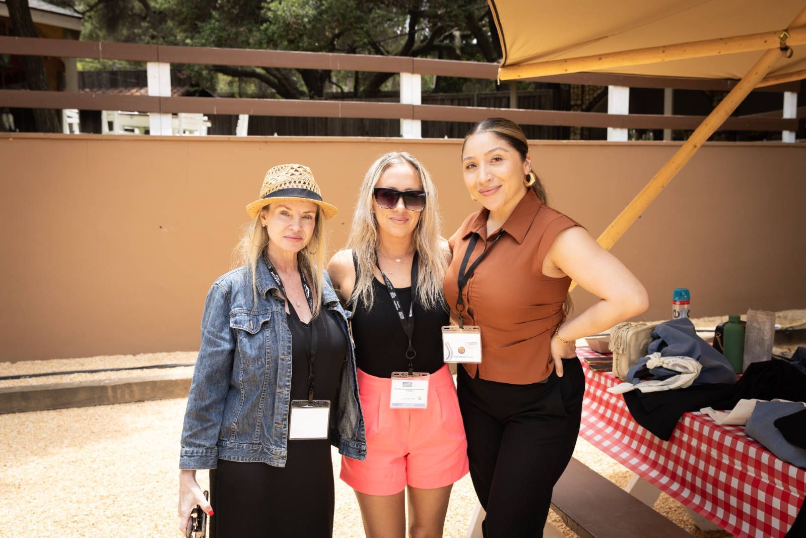 Three women are posing for a picture in front of a picnic table.